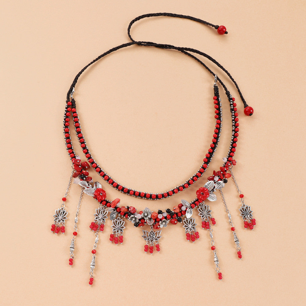 Boho red black braided cord choker necklace featuring red bead accents, intricate silver decorative tassel pendants, and adjustable red bead drawstring closure, displayed on a light yellow background, ideal for bohemian and trendy fashion styling in the US