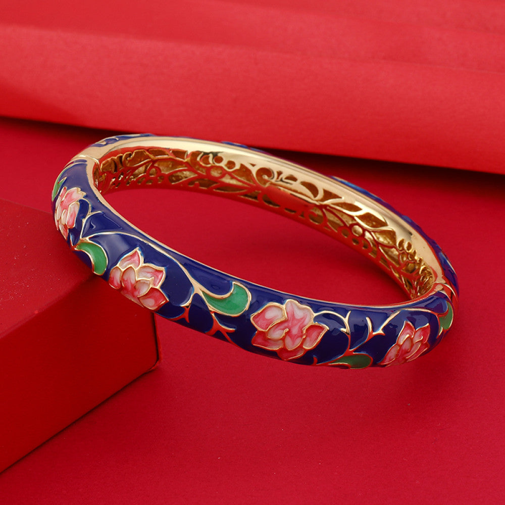 Boho vintage Chinese cloisonné enamel bangle with pink floral design and gold plating, styled on red background, ideal for ethnic and bohemian fashion enthusiasts in the US