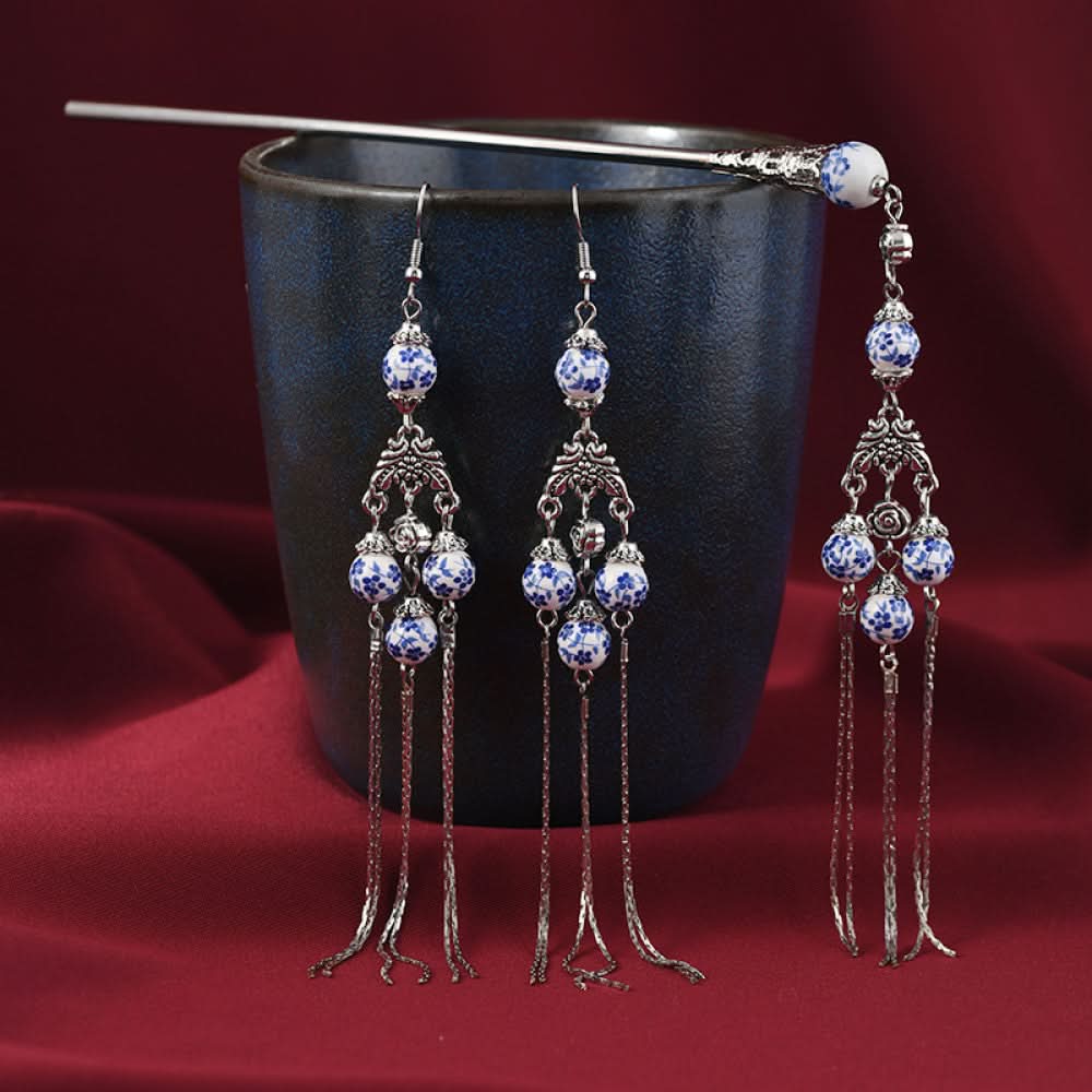 Boho vintage ethnic 3-piece set featuring silver-tone decor, blue-and-white porcelain-style beads, and layered chain tassel fringe, displayed beside a dark blue vessel on a rich red fabric background