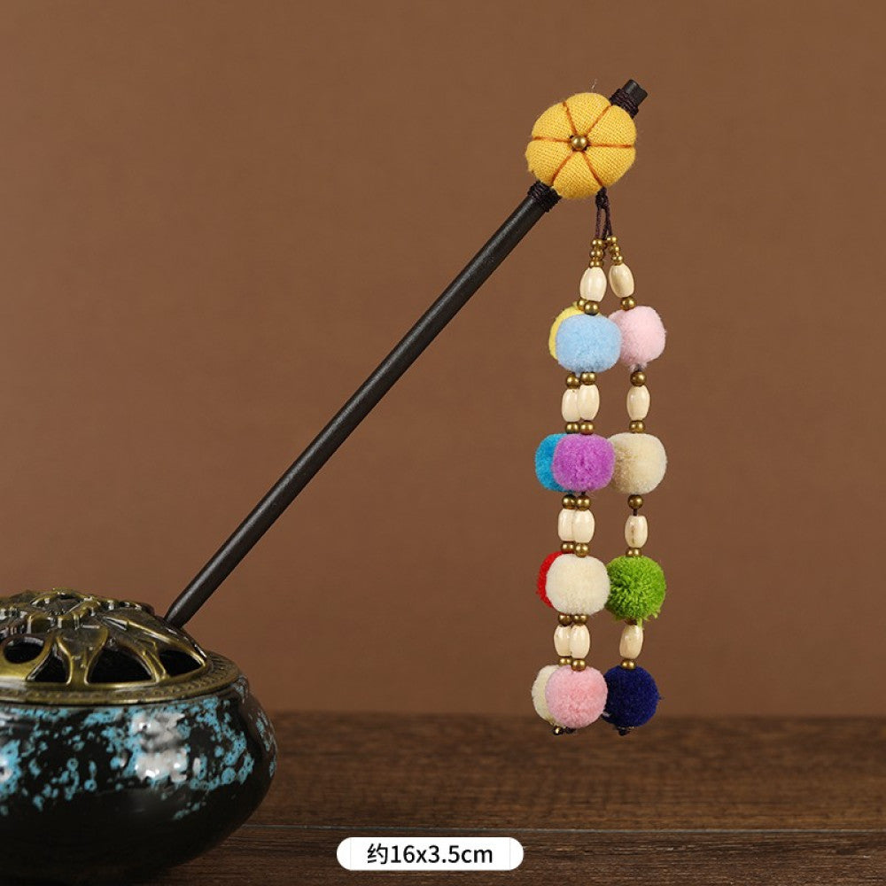 Boho vintage ethnic hair stick pendant featuring colorful pom poms, multi-color beaded accents, and a long orange tassel, displayed alongside an incense burner on a wooden surface against a brown background, ideal for bohemian and traditional fashion enthusiasts in the US 02