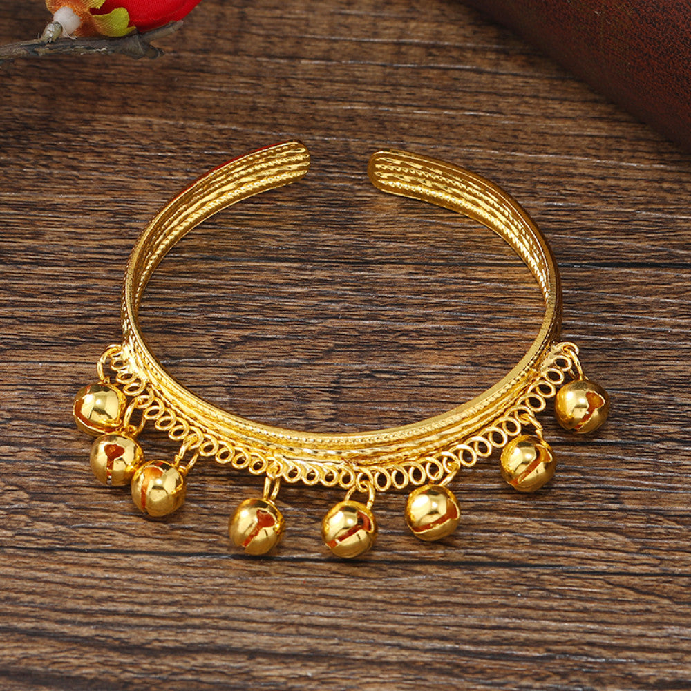 Boho vintage ethnic gold cuff bangle with bell charms, styled on a vintage book, ideal for bohemian and ethnic fashion enthusiasts in the US 01