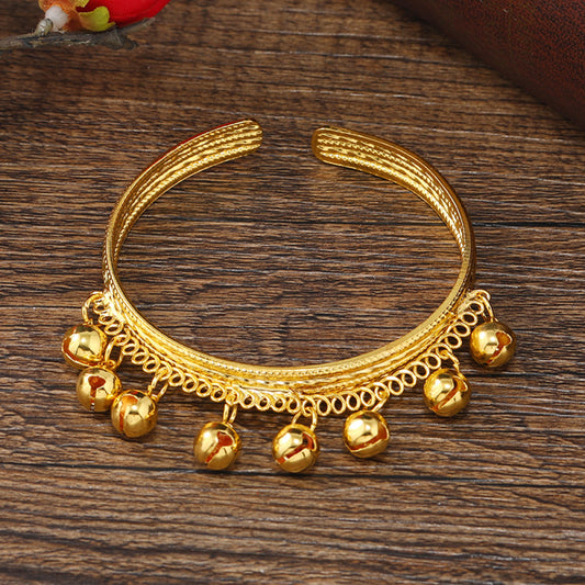 Boho vintage ethnic gold cuff bangle with bell charms, styled on a vintage book, ideal for bohemian and ethnic fashion enthusiasts in the US 01