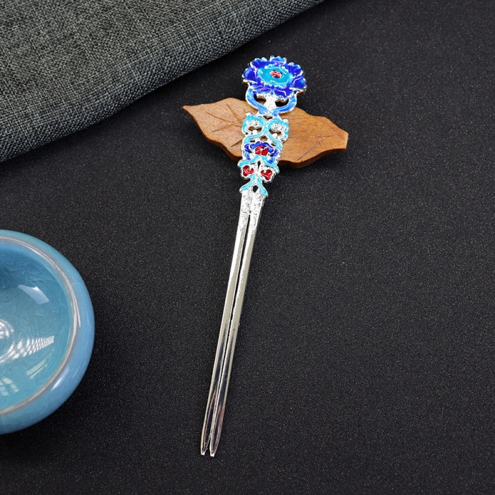 Boho vintage ethnic gold-tone double hair stick featuring vibrant enamel decor (blue/green/red tones) and gemstone accents, displayed on a dark fabric background (paired with a blue ceramic bowl & wooden leaf decor), ideal for bohemian and traditional fashion enthusiasts in the US 01