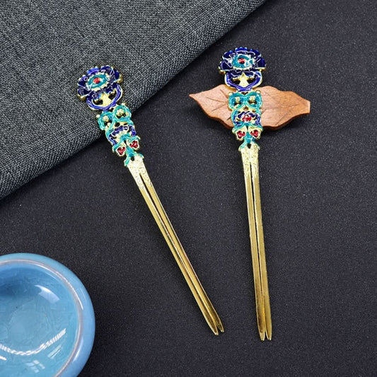 Pair of boho vintage ethnic gold-tone double hair sticks, featuring vibrant colorful enamel and gemstone accents, displayed on a dark fabric background
