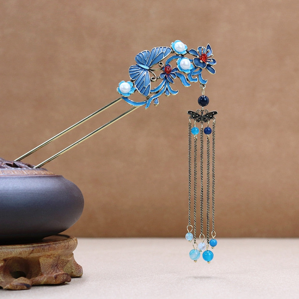 Boho vintage ethnic gold-tone double hair stick featuring a blue phoenix charm (with white flower & red center), pearl accent, birdcage pendant, and blue/white beaded tassels, displayed alongside a ceramic vessel on a warm brown background, ideal for bohemian and traditional fashion enthusiasts in the US 01