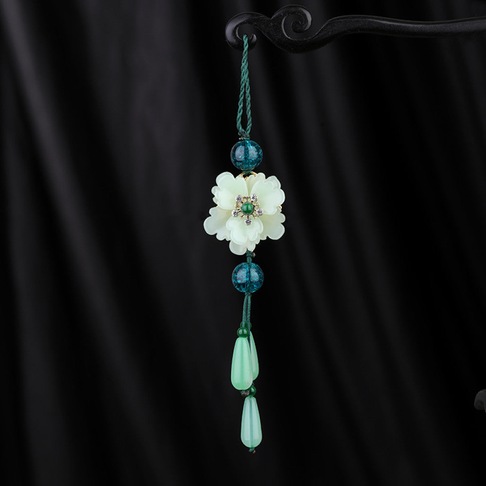 Boho vintage ethnic green-tone hair pendant featuring green cord, dark teal decorative beads, white flower charm (with gemstone center), and light green teardrop pendants, styled against a black fabric background, ideal for bohemian and traditional fashion enthusiasts in the US