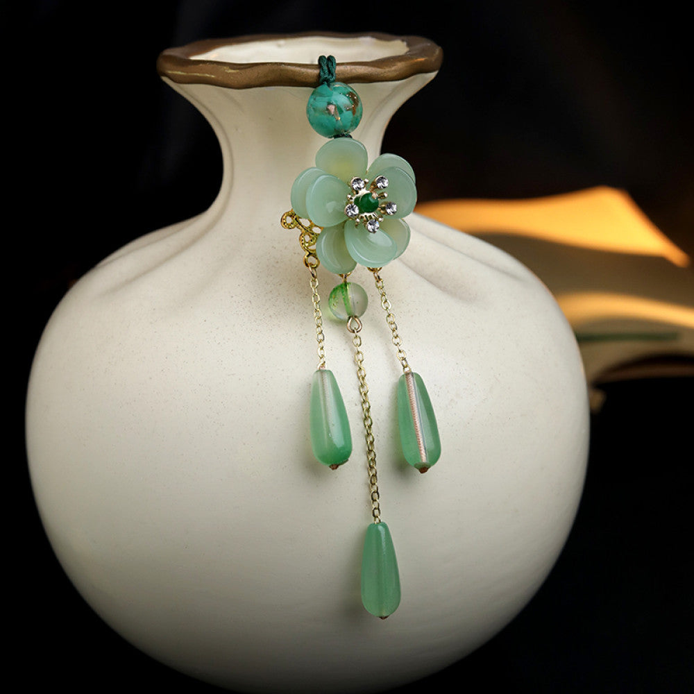 Boho vintage ethnic green-tone hair pendant featuring green cord, turquoise bead, white flower-shaped charm (with green gemstone and diamond center, gold trim), and gold-accented green teardrop pendants on chain tassels, styled against a dark brown fabric background, ideal for bohemian and traditional fashion enthusiasts in the US 02