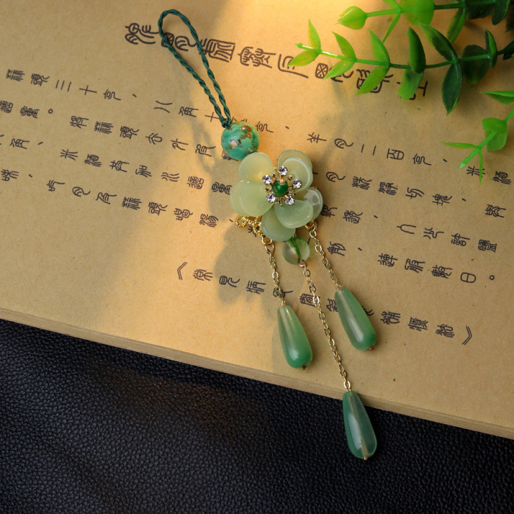 Boho vintage ethnic green-tone hair pendant featuring green cord, turquoise bead, white flower-shaped charm (with green gemstone and diamond center, gold trim), and gold-accented green teardrop pendants on chain tassels, styled against a dark brown fabric background, ideal for bohemian and traditional fashion enthusiasts in the US 03