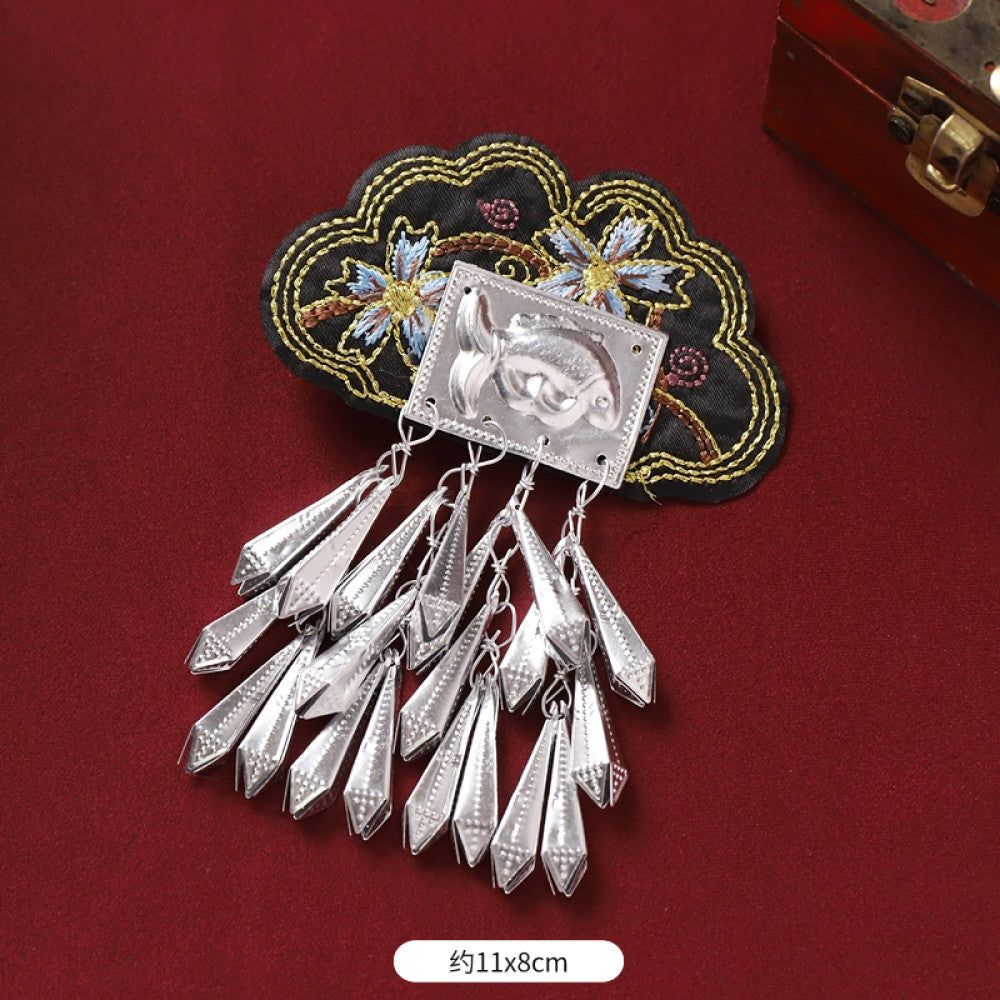 Boho vintage ethnic silver-tone decorative brooch featuring an intricate butterfly charm, pink floral embroidered accent (with blue details), and bell tassel pendants, displayed on a red fabric background 04
