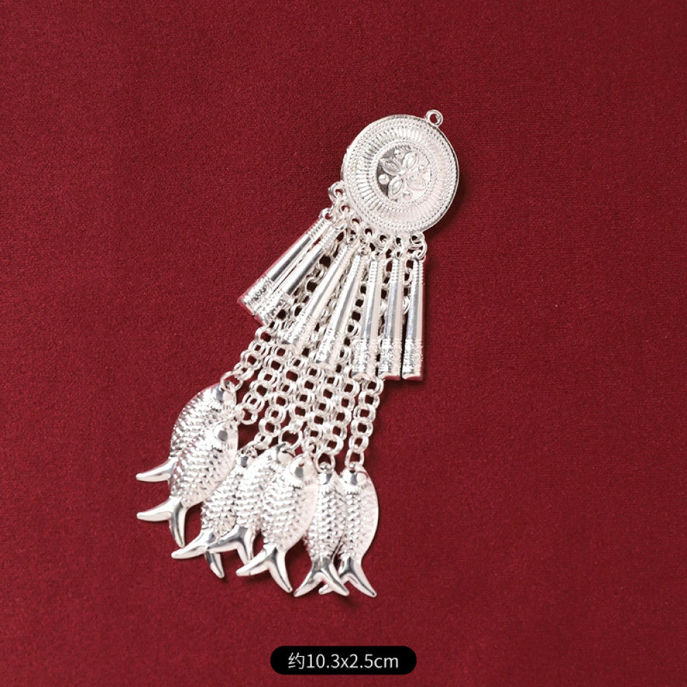 Boho vintage ethnic silver-tone decorative pendant featuring an intricate round patterned center, multiple silver-tone fish charms, and layered bell tassel fringe, displayed on a rich red fabric background, ideal for bohemian and traditional fashion styling in the US