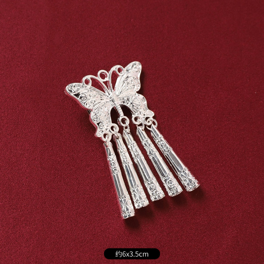 Boho vintage ethnic silver-tone decorative pendant featuring an intricate round patterned center, multiple silver-tone fish charms, and layered bell tassel fringe, displayed on a rich red fabric background, ideal for bohemian and traditional fashion styling in the US 01