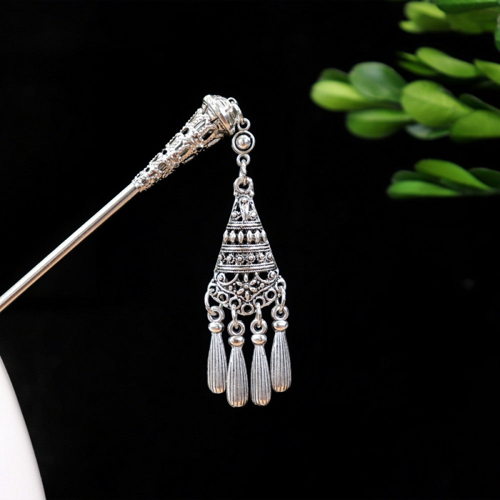 Boho vintage ethnic silver-tone hair stick featuring turquoise beads, an intricate round decorative element, and layered chain tassel fringe, displayed beside a white vessel green foliage 02