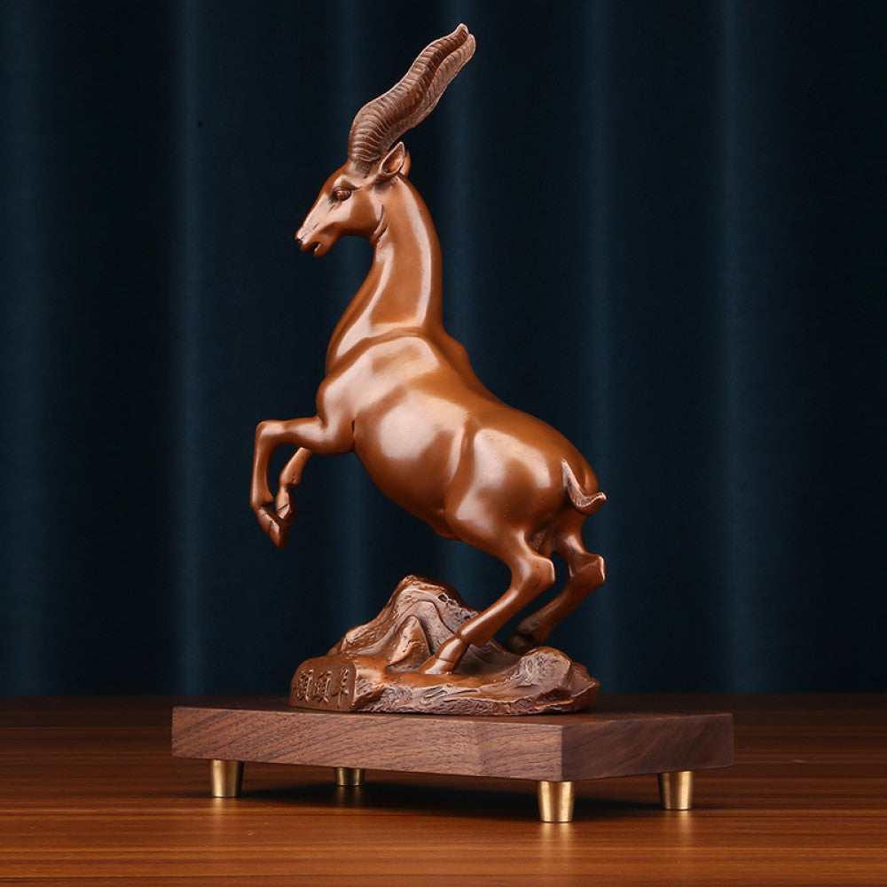 Bronze antelope statue with a leaping stance, a Feng Shui symbol of success and strength, displayed on a wooden base as elegant home decor against a dark blue background 02