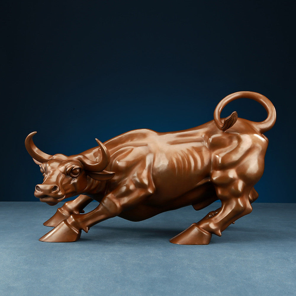 Bronze bull statue with a dynamic charging stance, a Feng Shui symbol of strength and financial fortune, displayed as elegant home decor against a dark blue background