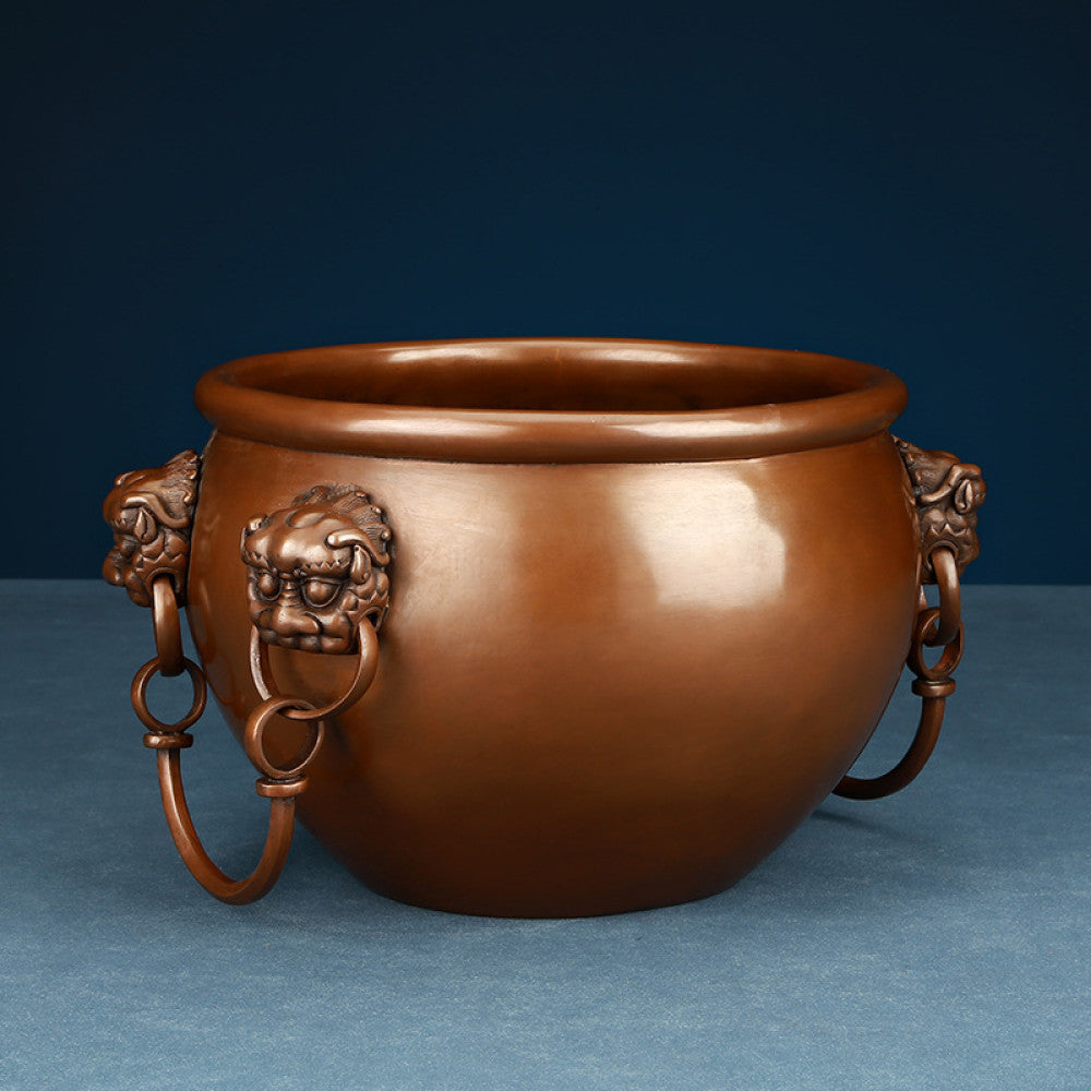 Polished bronze Chinese decorative vessel with intricate beast-head handles and hanging rings, a Feng Shui symbol of wealth and protection, displayed as elegant home decor against a white background 01