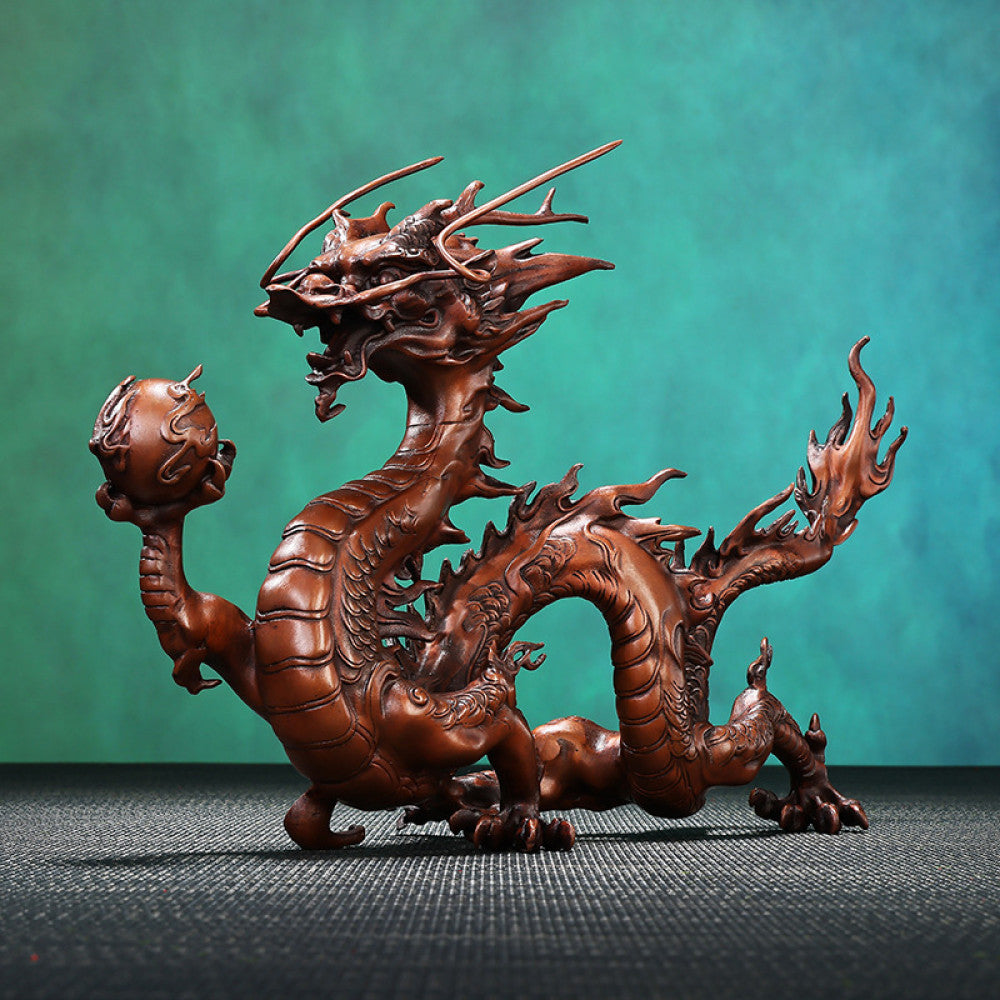Intricate bronze Chinese dragon statue holding a pearl, a Feng Shui symbol of good fortune and strength, displayed as elegant home decor in a natural-inspired setting against a green background 01
