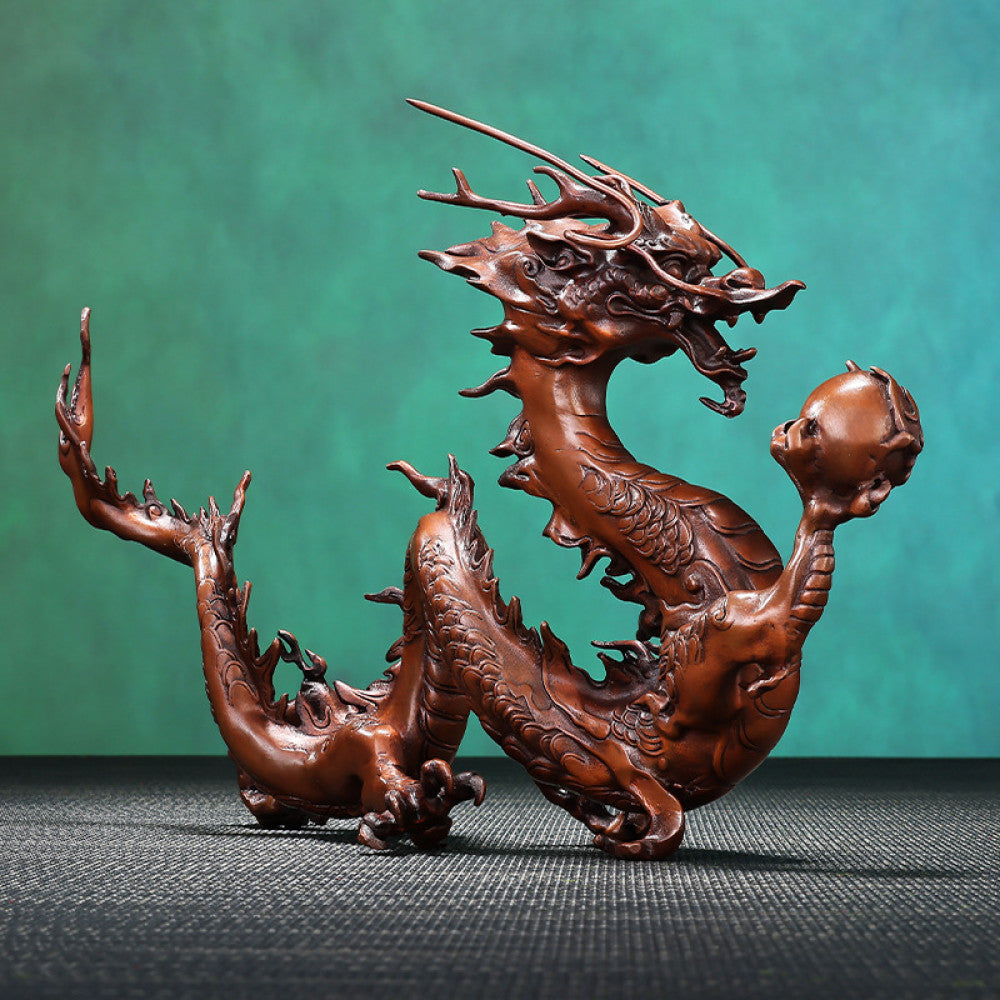 Intricate bronze Chinese dragon statue holding a pearl, a Feng Shui symbol of good fortune and strength, displayed as elegant home decor in a natural-inspired setting against a green background 02