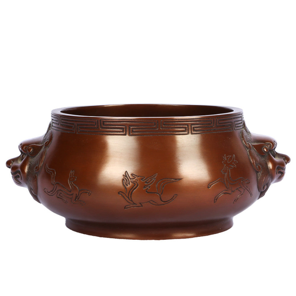 Intricate bronze Chinese incense burner with beast-head handles and traditional patterns, a Feng Shui symbol of wealth and harmony, displayed as elegant home decor against a white background