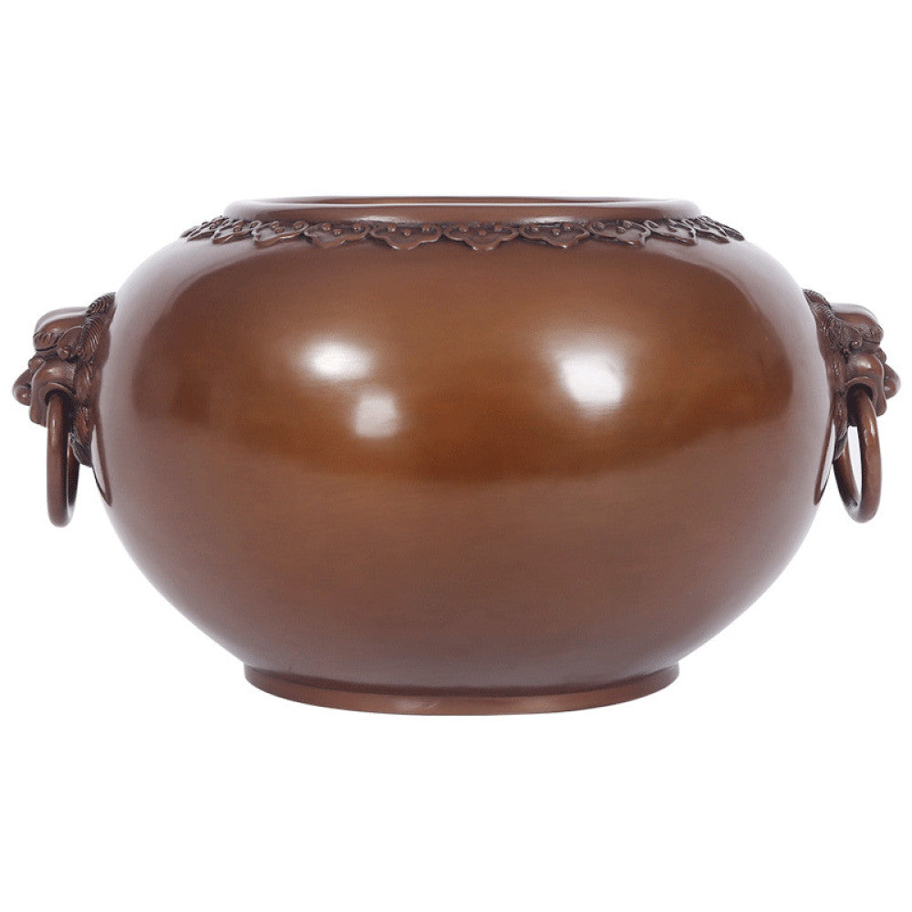 Polished bronze Chinese incense burner with intricate beast-head handles and decorative rim, a Feng Shui symbol of wealth and protection, displayed as elegant home decor against a dark blue background on a textured surface 06