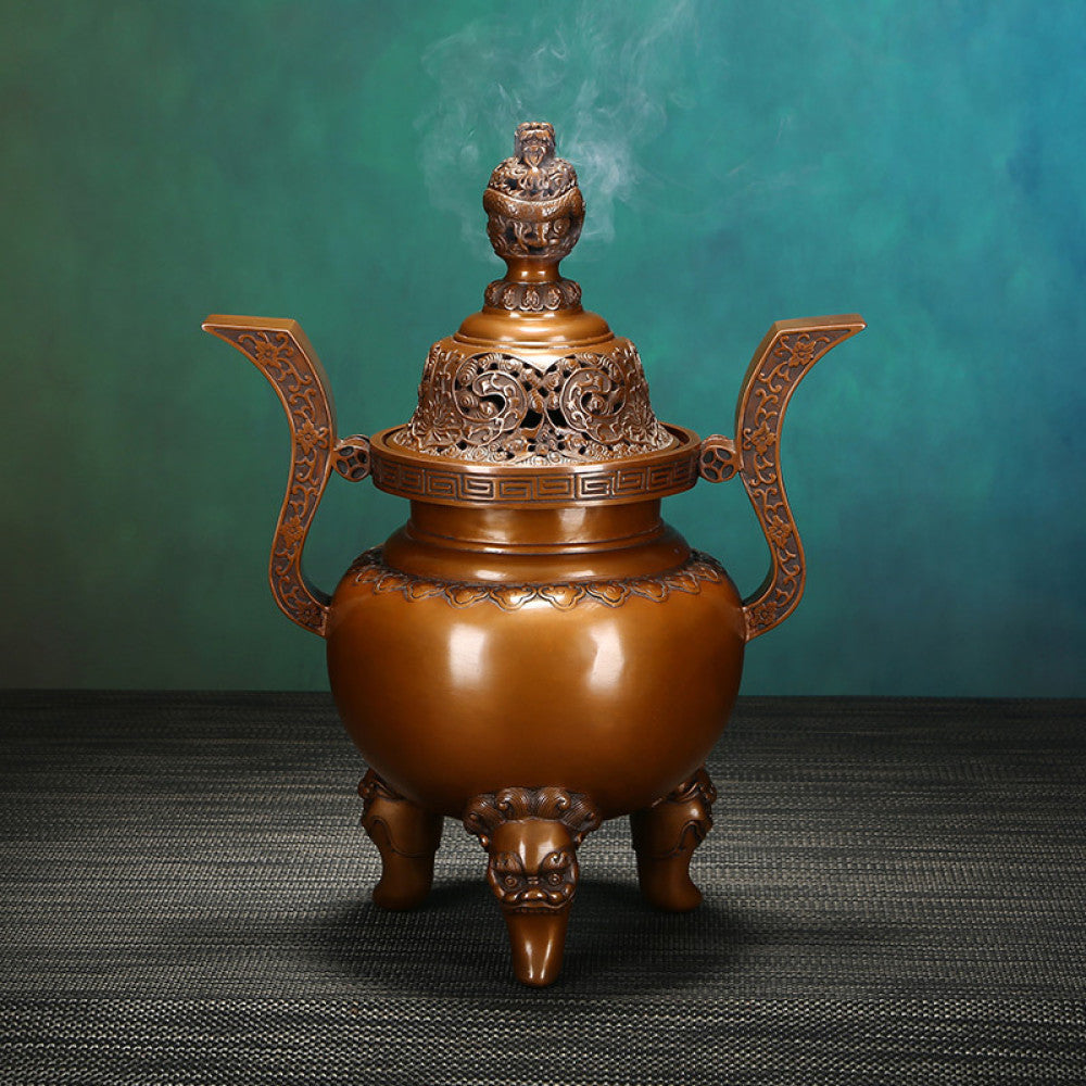 Intricate bronze Chinese incense burner with dragon-topped pierced lid, ornate curved handles, and lion-shaped feet, a Feng Shui symbol of wealth and elegance, displayed as a sophisticated home decor piece against a teal textured background 01