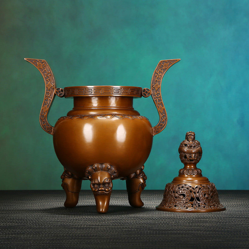 Intricate bronze Chinese incense burner with dragon-topped pierced lid, ornate curved handles, and lion-shaped feet, a Feng Shui symbol of wealth and elegance, displayed as a sophisticated home decor piece against a teal textured background 05