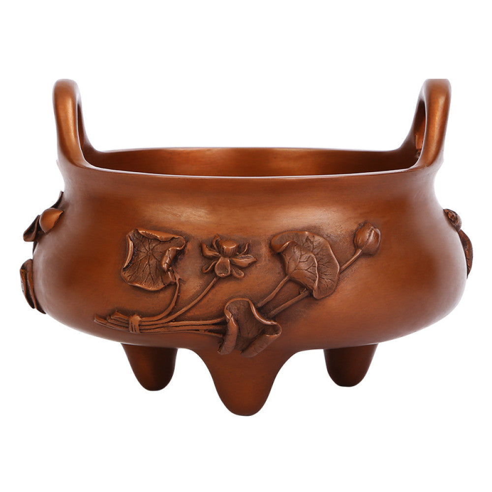 Intricate bronze Chinese incense burner with raised lotus flower carvings, curved handles, and three feet, a Feng Shui symbol of wealth and harmony, displayed as elegant home decor on a textured surface against a teal background 04