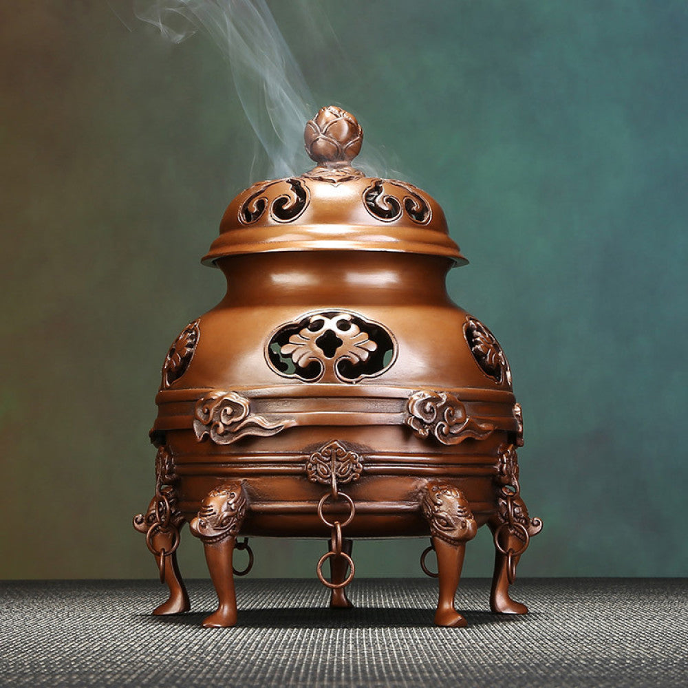Intricate bronze Chinese incense burner with lotus-topped pierced lid, elaborate cloud carvings, and beast-shaped feet, emitting incense smoke, a Feng Shui symbol of wealth and harmony, displayed as a sophisticated home decor piece against a textured teal background