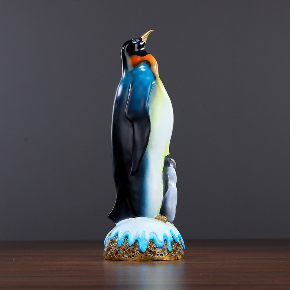 Colorful penguin statue featuring an adult penguin and a chick, designed as a charming home decor accent piece with a snow - themed base, displayed on a wooden surface against a gray background 01