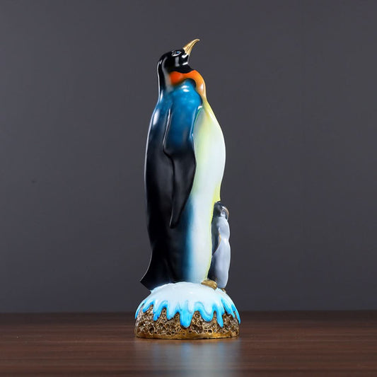 Colorful penguin statue featuring an adult penguin and a chick, designed as a charming home decor accent piece with a snow - themed base, displayed on a wooden surface against a gray background 01