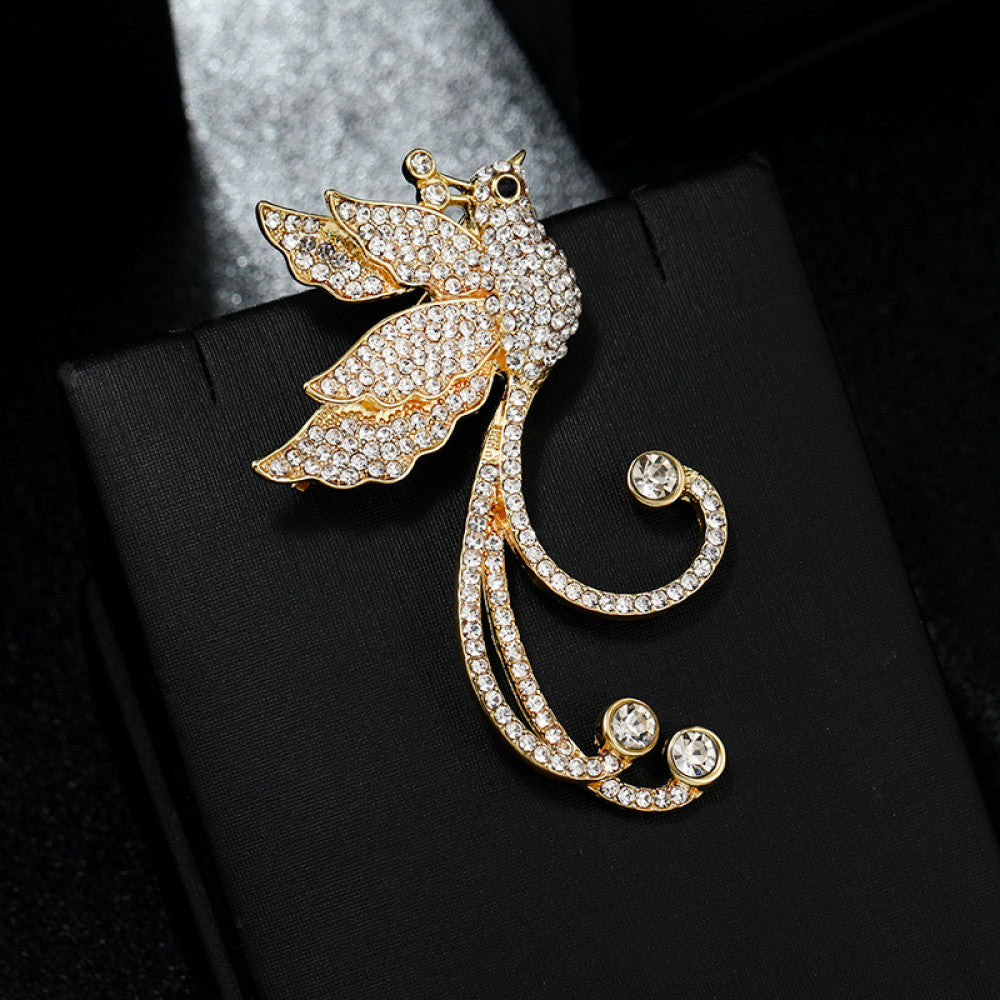 This elegant brooch features a sparkling crystal-encrusted bird in a gold-tone setting, accented by a lustrous pearl and delicate pink detail at its head. A sophisticated statement piece for any outfit 02