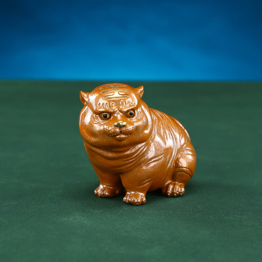 Cute brown chubby tiger figurine with intricate details, a symbol of good luck, placed on a green surface against a blue background