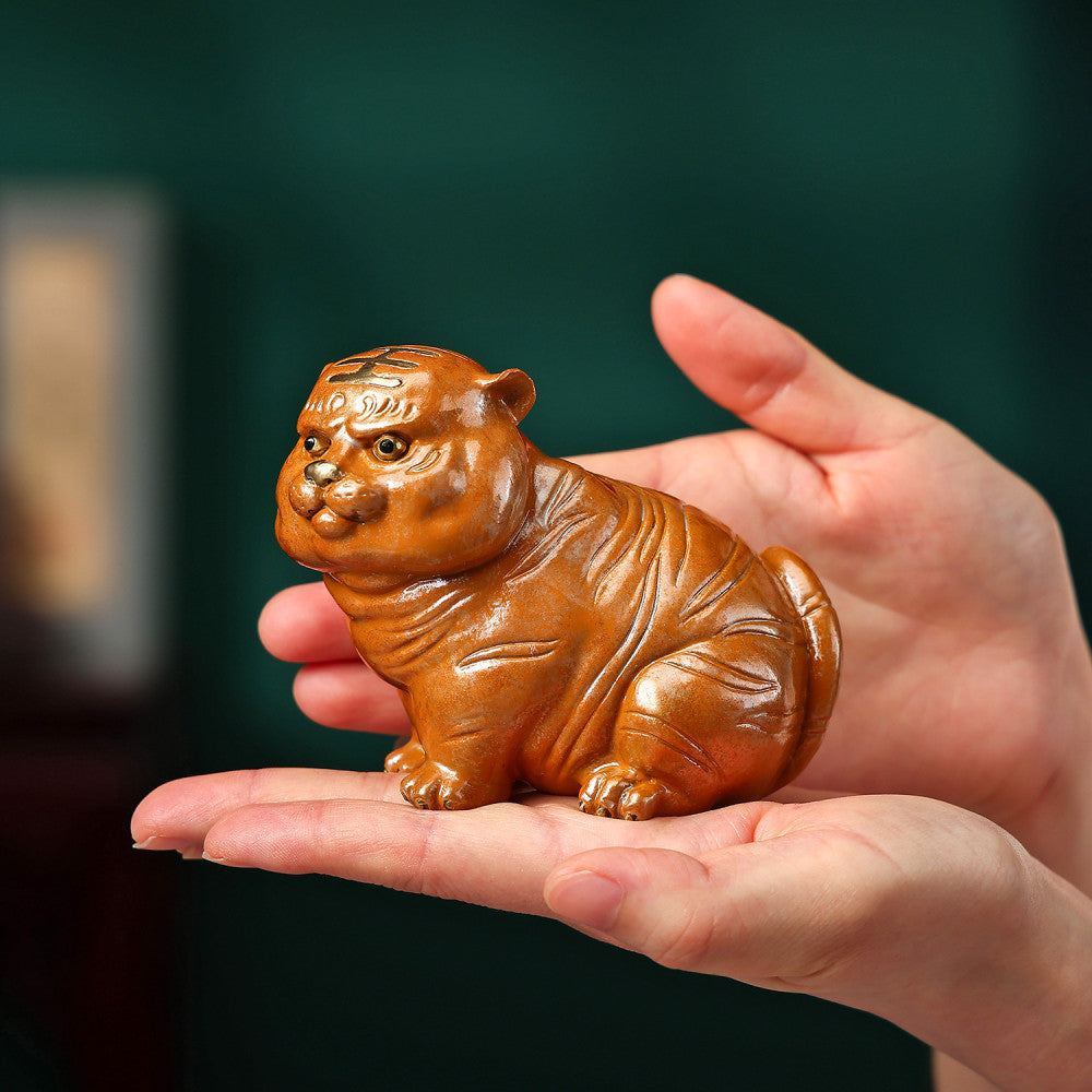 Cute brown chubby tiger figurine with intricate details, a symbol of good luck, placed on a green surface against a blue background 04