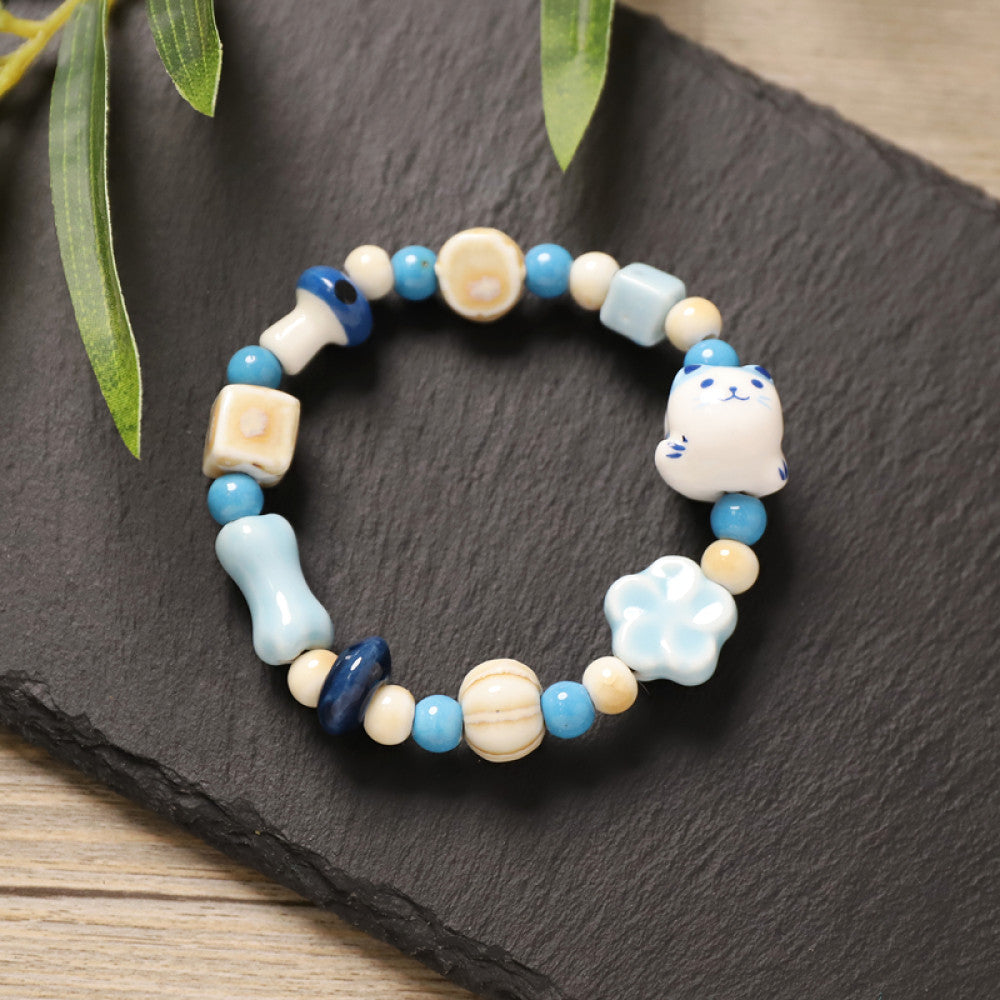 This playful beaded bracelet features a charming lucky cat ceramic bead at its center, paired with whimsical ceramic charms like stars, bones, and flowers, interspersed with small brown beads. Crafted from ceramic, it brings a cute, kawaii vibe to everyday outfits 02