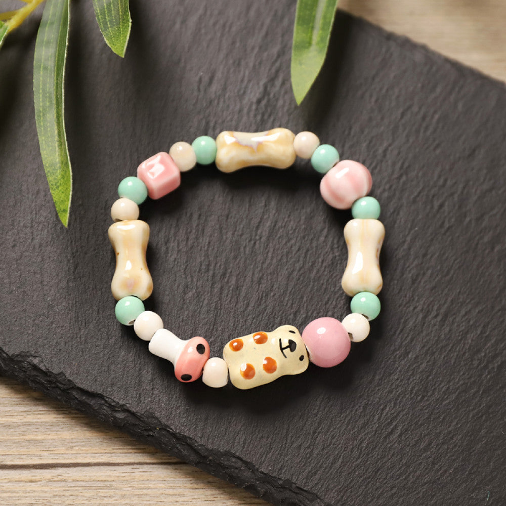 This playful beaded bracelet features a charming lucky cat ceramic bead at its center, paired with whimsical ceramic charms like stars, bones, and flowers, interspersed with small brown beads. Crafted from ceramic, it brings a cute, kawaii vibe to everyday outfits 04