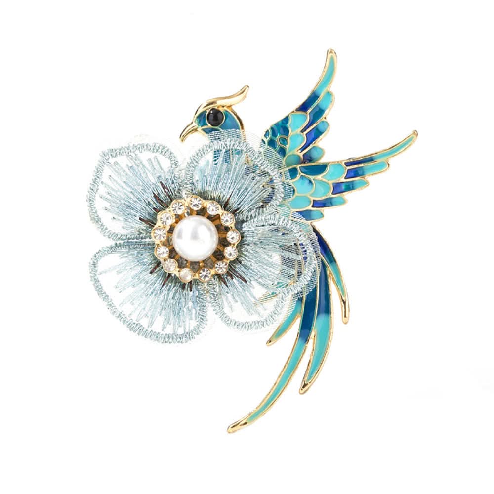 This exquisite brooch features a graceful enamel bird in vibrant blue hues, perched beside a delicate lace flower. The flower’s center is adorned with a lustrous pearl, surrounded by a halo of sparkling crystals, creating a stunning contrast of textures and colors. Perfect for adding a touch of whimsical elegance to blazers, scarves, or special occasion outfits, this piece blends intricate craftsmanship with timeless, eye-catching charm 03