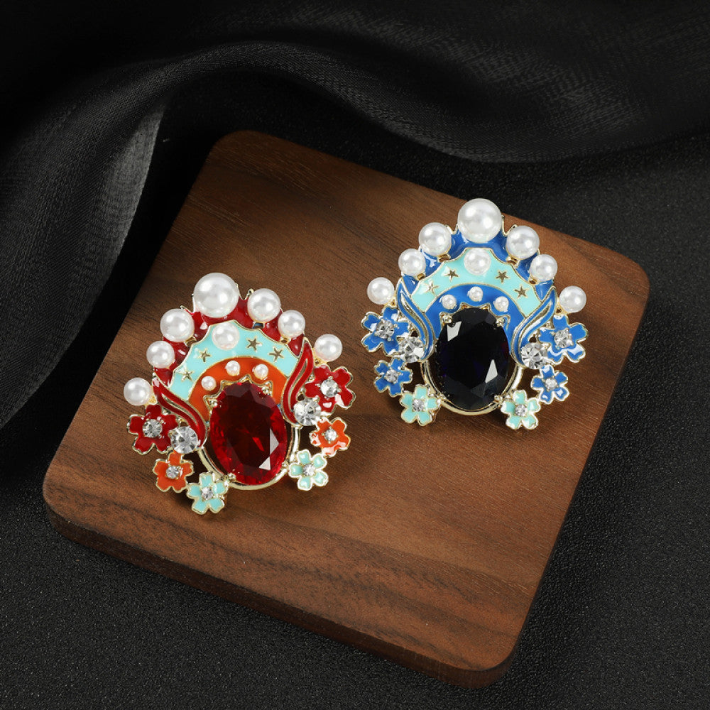 This striking brooch features a bold, theatrical-inspired design with vibrant enamel, lustrous pearls, and a prominent red crystal at its center. Delicate floral motifs and sparkling crystals add intricate detail, making it a standout accessory for blazers, scarves, or dresses. Perfect for adding a pop of color and artistic flair to any outfit, this piece is sure to make a memorable statement. 03