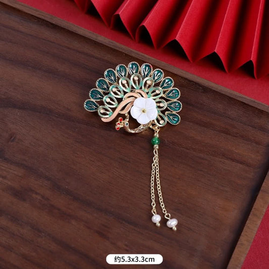 This elegant brooch features a delicate fan-shaped design, crafted with a gold-tone metal frame and adorned with vibrant multicolored gemstones. A lustrous pearl anchors the center, from which three graceful gold chains dangle, each finished with a small pearl drop. Perfect for adding a touch of sophistication to blazers, scarves, or special occasion outfits, this piece blends intricate craftsmanship with timeless, eye-catching charm. 01