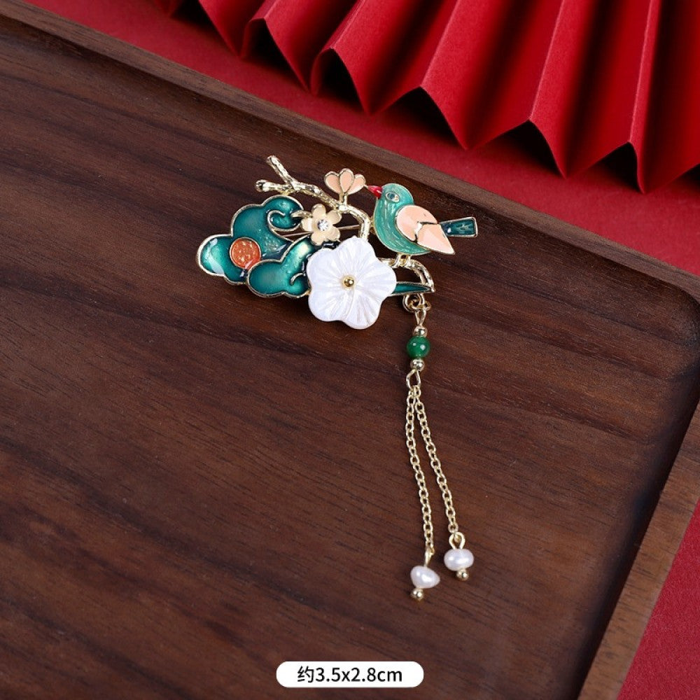 This elegant brooch features a delicate fan-shaped design, crafted with a gold-tone metal frame and adorned with vibrant multicolored gemstones. A lustrous pearl anchors the center, from which three graceful gold chains dangle, each finished with a small pearl drop. Perfect for adding a touch of sophistication to blazers, scarves, or special occasion outfits, this piece blends intricate craftsmanship with timeless, eye-catching charm 02