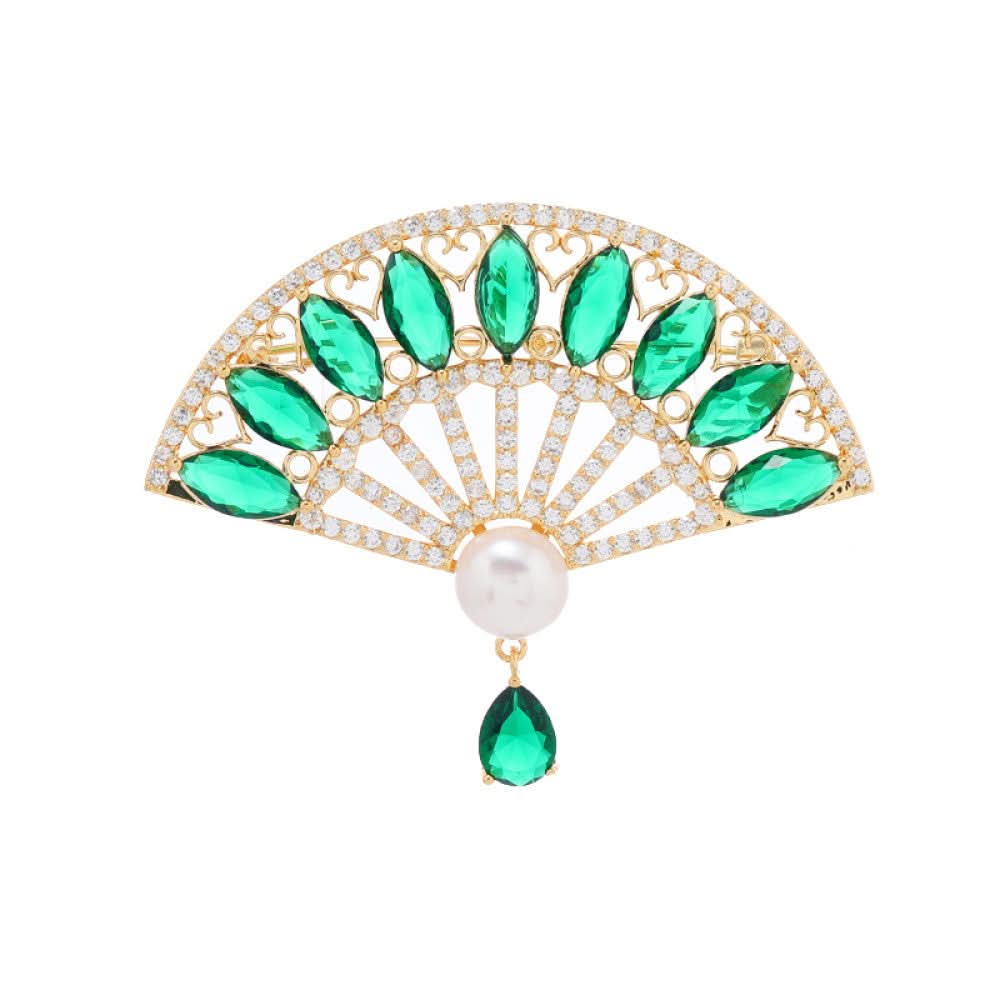 This elegant brooch features a striking fan-shaped design, crafted with a gold-tone metal base. It is adorned with vibrant emerald-green gemstones, shimmering clear crystals, and a lustrous pearl at the center, from which a teardrop-shaped green gem dangles gracefully. Perfect for adding a touch of sophistication to blazers, scarves, or evening wear, this piece blends timeless elegance with a bold, eye-catching silhouette. 0