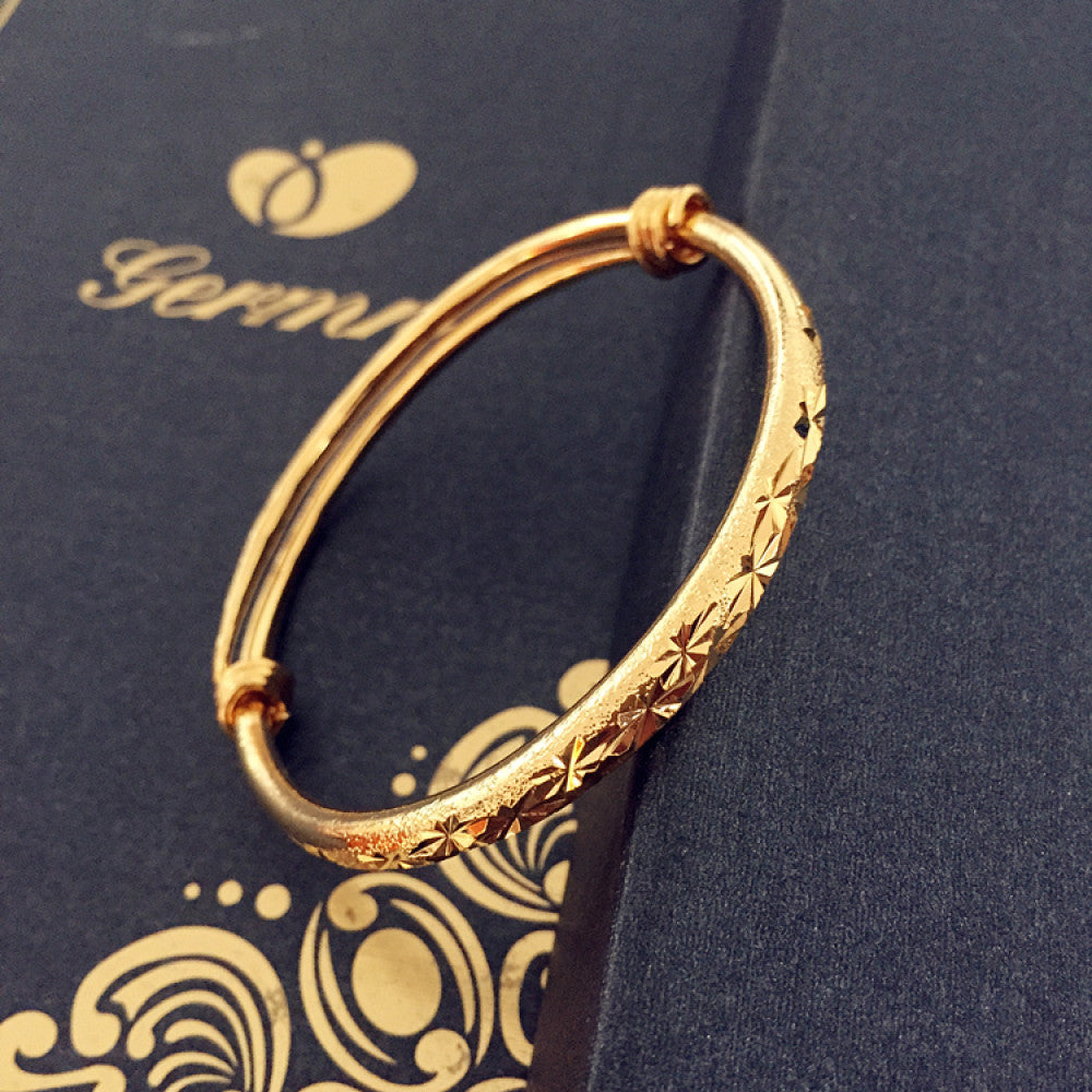 Fashion luxury engraved gold bangle, styled on a decorative black surface, ideal for elegant fashion enthusiasts in the US