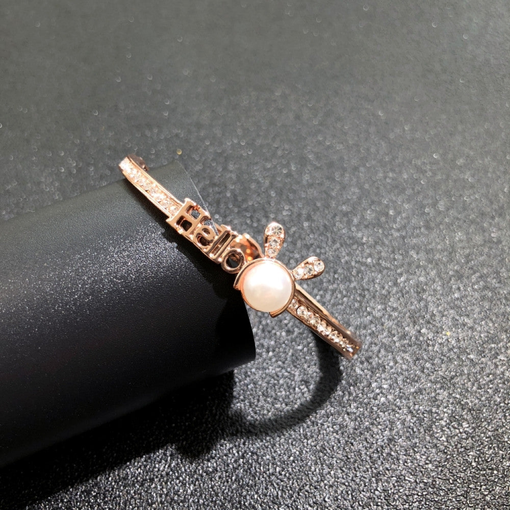 Fashion luxury rose gold bangle with diamond-encrusted signature logo, displayed on black surface, ideal for luxury fashion and statement jewelry enthusiasts 04