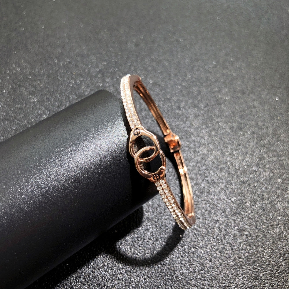 Fashion luxury rose gold bangle with diamond-encrusted signature logo, displayed on black surface, ideal for luxury fashion and statement jewelry enthusiasts 09