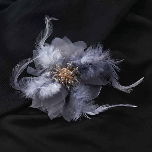 This hair accessory features light white feathers and sheer tulle, layered like a blooming flower. The center is adorned with sparkling crystals and pearls, creating a dreamy, ethereal look perfect for bridal styles or special occasions. 01