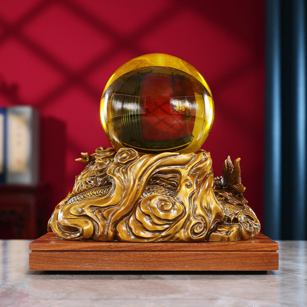 Golden dragon crystal ball statue with intricate carvings, a Feng Shui symbol of good fortune, displayed as elegant home decor on a wooden base against a red background