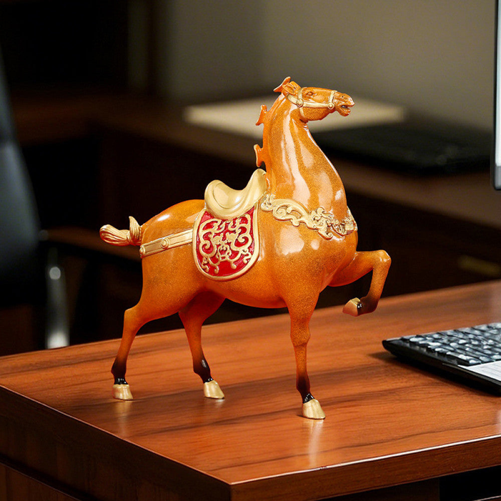 Chinese - style fortune horse statue with red emblem and golden details, displayed as decor on a wooden desk in an office space, symbolizing good luck and success