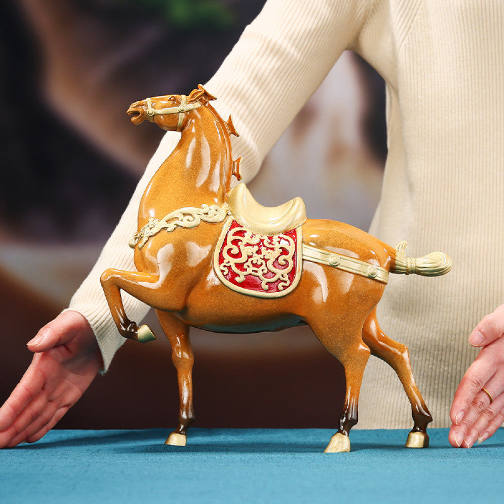 Chinese - style fortune horse statue with red emblem and golden details, displayed as decor on a wooden desk in an office space, symbolizing good luck and success 01
