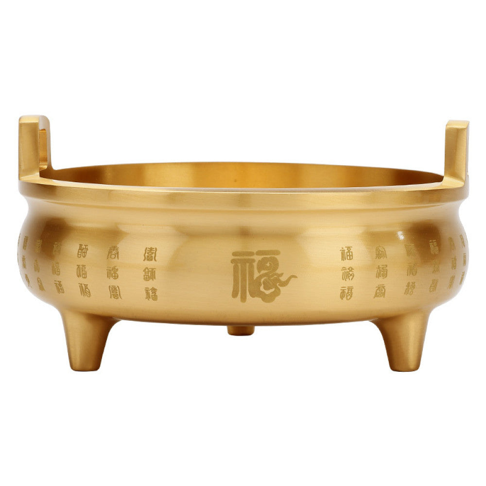 Golden bronze Chinese incense burner with double handles, three feet, and intricate fortune character carvings, a Feng Shui symbol of wealth and good luck, displayed as elegant home decor against a white background