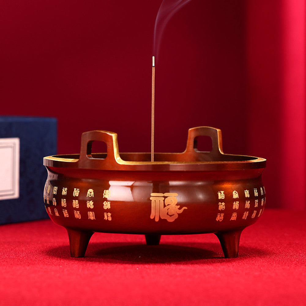 Golden bronze Chinese incense burner with double handles, three feet, and intricate fortune character carvings, a Feng Shui symbol of wealth and good luck, displayed as elegant home decor against a white background 01