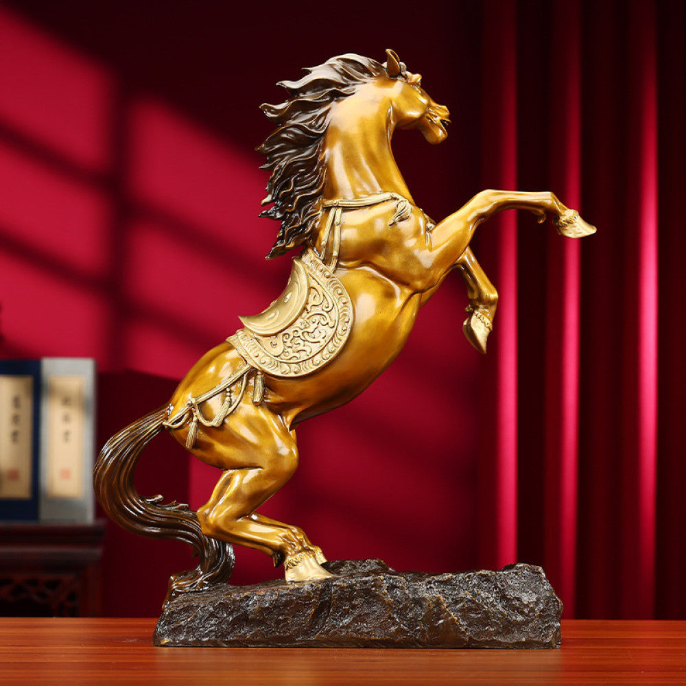 Golden horse statue with intricate saddle details, a Feng Shui symbol of success and good fortune, displayed as elegant home decor against a red background