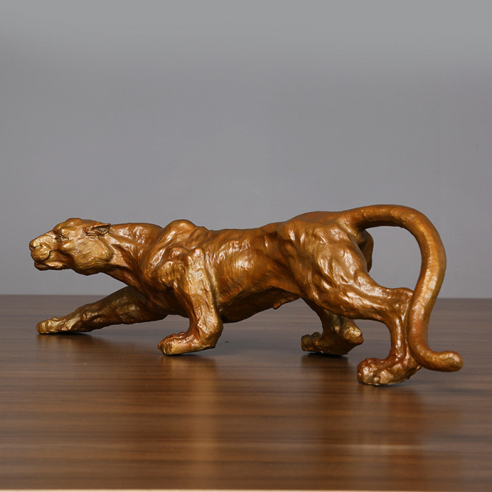 Golden panther statue with a dynamic running pose, featuring a metallic finish, ideal as an Art Deco home decor piece symbolizing strength and courage, displayed on a wooden surface against a gray background